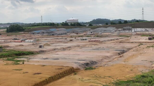 A vast land development site for a large scale terraced house project. Cleared land is prepared for new housing units. Nearby areas show ongoing residential construction in progress.