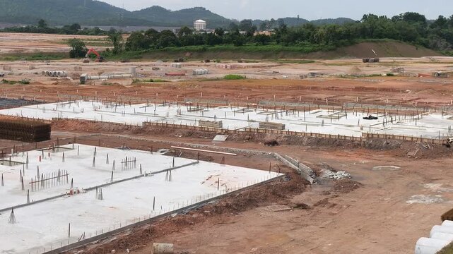 A vast land development site for a large scale terraced house project. Cleared land is prepared for new housing units. Nearby areas show ongoing residential construction in progress.