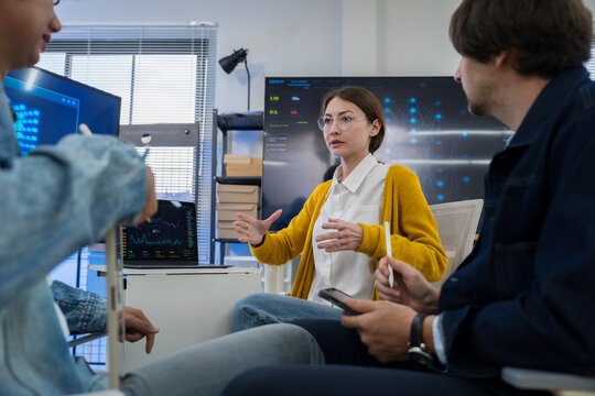 Caucasian woman explaining digital project ideas to multicultural colleagues during a tech team meeting.