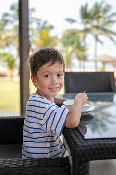 Sunny outdoor dining scene with a joyful 5-year-old boy enjoying a meal