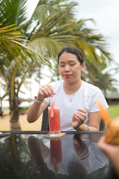 Relaxing beachside atmosphere with Asian woman enjoying a fruity drink