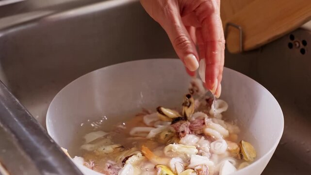 Bare Hand Rinses Mussels Squid and Shrimp in a Bowl at a Kitchen Sink, Showing Fresh Food Preparation and Hygiene Slow motion