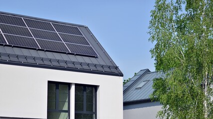 Fototapeta premium Modern Home with Rooftop Solar Panels and Green Trees Under Blue Sky