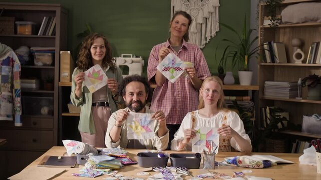 Portrait of Caucasian adults showing handmade patchwork blocks in craft studio. Clip is perfect for promoting creative education, DIY hobby classes, or art workshops