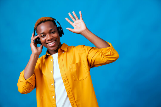 Portrait of young Black woman wearing headphones, smiling at camera and waving while listening to audio. Ideal for music streaming, podcast promotion, youth marketing, medium shot