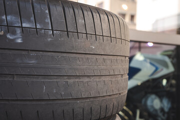 Tight close up view of automobile tire tread patterns and rubber surface grooves on stacked tires outside a garage shop. © Octavian