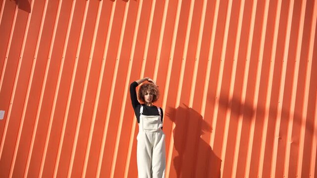 A child is playfully hanging from an orange wall, radiating joy and carefree energy