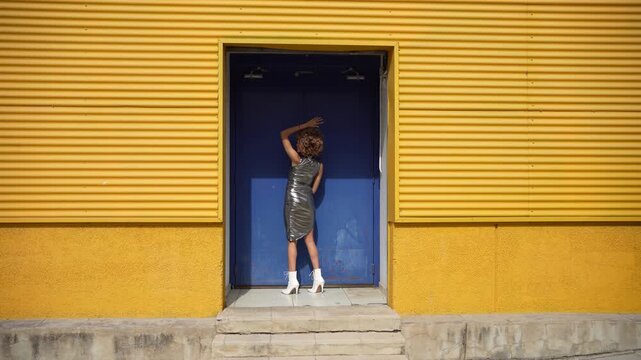 A Fashionable Woman Posing Stylishly in Front of a Bright and Cheerful Yellow Wall