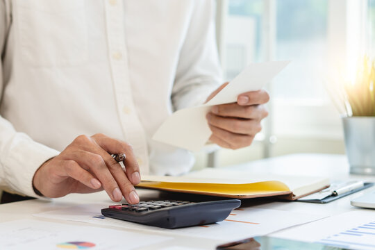 Deduction planning, debt asian accountant hand using calculator to calculating money balance from bill and income, cost budget expenses for pay money form personal individual on table at home.
