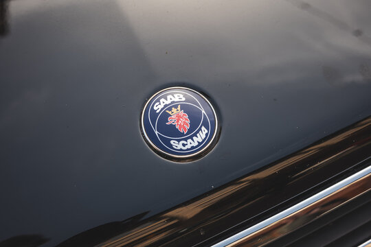 Lindau, Switzerland, August 9, 2026. Close up view of vintage Saab Scania badge on glossy black bonnet.