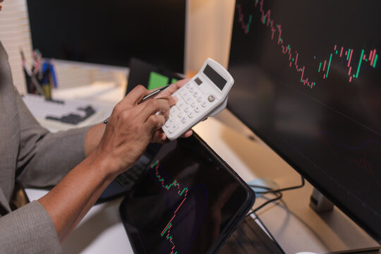 Professional stock trader reviewing market charts with sticky notes across multiple monitors, laptop, and tablet to analyze price trends, plan trading strategies, and manage investment decisions.