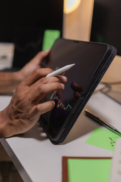 Professional stock trader reviewing market charts with sticky notes across multiple monitors, laptop, and tablet to analyze price trends, plan trading strategies, and manage investment decisions.