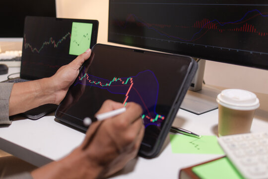 Professional stock trader reviewing market charts with sticky notes across multiple monitors, laptop, and tablet to analyze price trends, plan trading strategies, and manage investment decisions.