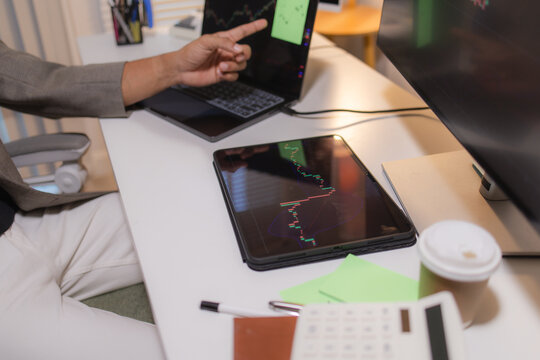 Professional trader analyzing stock market charts on laptop, tablet, and monitor while reviewing candlestick patterns, technical indicators, and market trends to support informed investment decisions.
