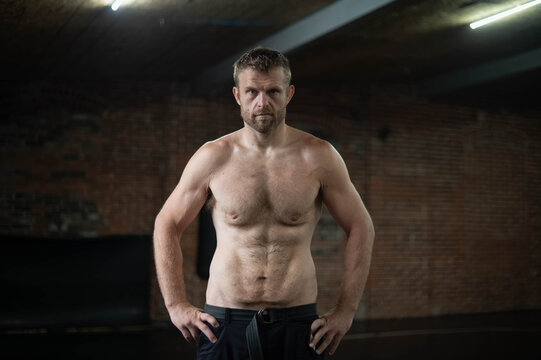Fit man in a dark lit boxing martial arts gym, sports, fight, wellness active, copy space authentic real people, man after loosing weight, dad bod
