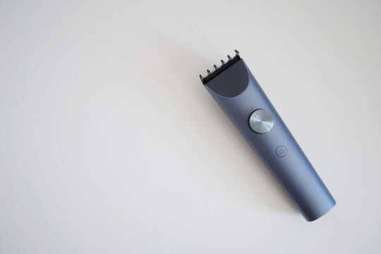 Modern wireless hair clipper with short comb attachment on white background