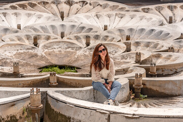 A woman is traveling in Armenia, near a sculptural stone fountain with overlapping bowls featuring relief patterns at the entrance to the metro station. © KseniaJoyg