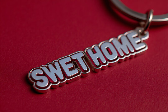 Quirky Metallic 'SWET HOME' Keychain on Deep Red Textured Background