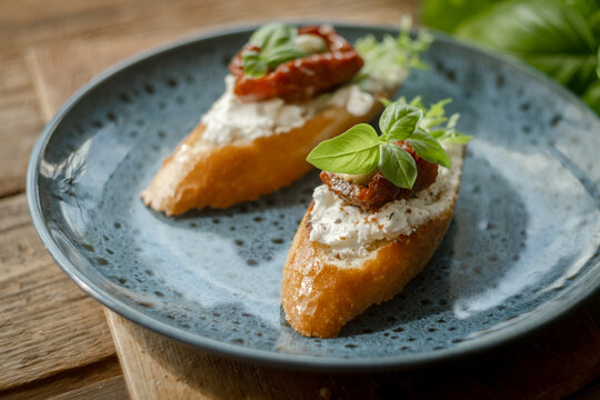 Bruschetta or crostini with feta, sun-dried tomatoes, olives and fresh herbs. Tasty healthy snacks for breakfast