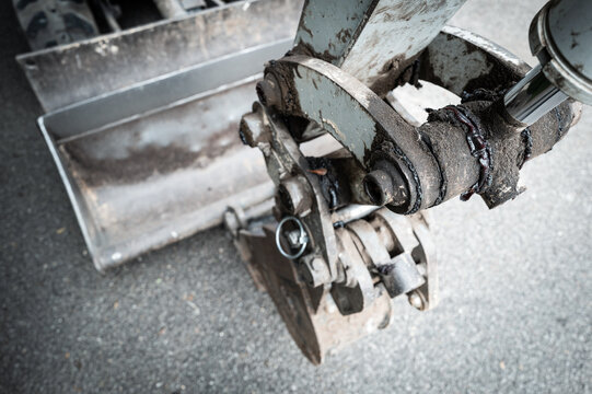 Shallow focus of a lubricated hydraulic joint seen on a mechanical digger on a roadway. Grease is seen around the pivot joint following a service.