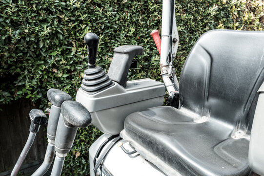 Detailed view of the driving seat and control levers and joysticks of a modern mechanical digger and excavator. The levers control the hydraulic scoop while the joystick controls the steering.