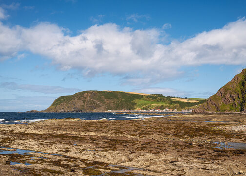 Crovie fishing village seen from the rocky coastline of Gardenstown on a clear sunny day in Aberdeenshire Scotland with blue sky and sea