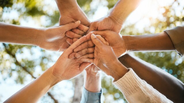 Diverse people joining hands together in circle symbolizing unity teamwork community support and collaboration outdoors