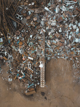 Aerial view of Agnesberg scrap metal yard featuring piles of rusted iron, steel beams, and industrial waste on a brown earth ground in Gothenburg, Vastra Gotaland County, Sweden.