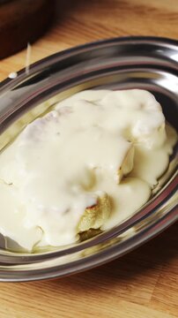 Silicone spoon pours white sauce over cauliflower. Cauliflower bake replaces pasta, rice or potatoes in low carb meal. Pair cauliflower bake with chicken, lean fish, fresh salad or green vegetables.
