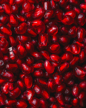 Macro close-up of glossy ruby red pomegranate seeds packed with vibrant color and juicy texture, creating a rich healthy food background ideal for antioxidant, nutrition and superfood themes.