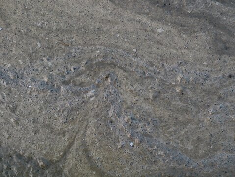 Close up texture of dirty foam and scum floating on the surface of muddy water in a paddy field, depicting environmental pollution, agricultural runoff, and natural soil wet abstract surface