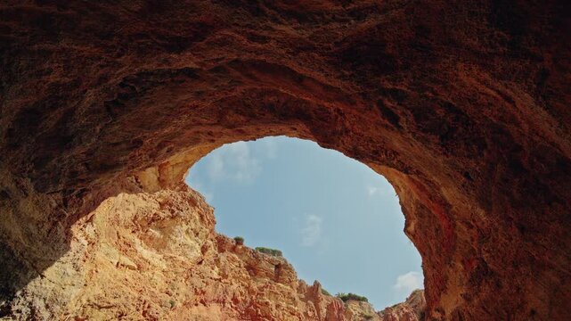 Natural skylight and golden limestone walls inside Gruta do Paraiso near Carvoeiro on the Algarve coast.