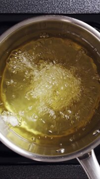 Chef drops battered shrimp into hot oil in restaurant kitchen. Battered shrimp fries to golden crust with juicy centre. Serve battered shrimp as tempura, seafood starter, tasting menu or chef special.