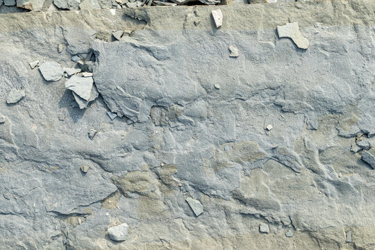 Quebec, Canada, 28 July 2026 : Close-up view of a textured grey rock surface with cracks and small detached fragments.