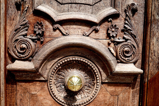 Porte d'entr&eacute;e avec menuiserie ancienne en bois sculpt&eacute; et bouton de porte en laiton dor&eacute;