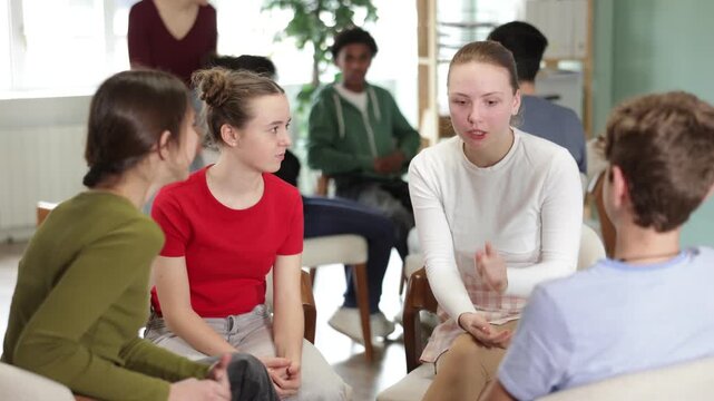 Two groups of students sit in a circle and discuss a topic, girls and boys communicate while the teacher watches in the background . High quality 4k footage