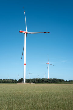 Wind turbines stand tall in a green field under a clear blue sky