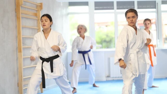  Women of different ages in kimono standing in fight stance during group karate training