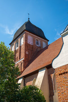 Historic Gothic Evangelical church built of red brick in Pasym, Masuria, viewed from below against a clear blue summer sky.