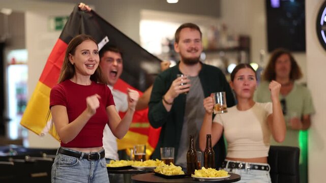Group of friends fans watching match cheering with German flag in bar