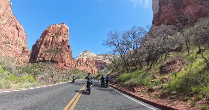 Scenic spring morning e-bike ride through Zion National Park in Utah, USA. Cyclists pedal along dramatic red rock canyons and green trails under soft morning light in this stunning national park lands