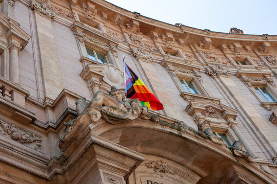 Palazzo Marino Facade Detail with Stone Statues and Rainbow Flag Piazza della Scala Milan Italy.