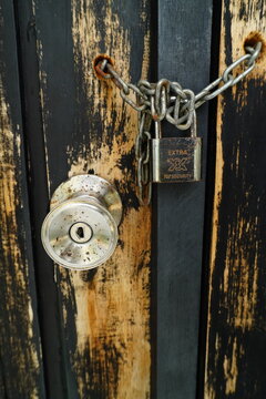 Weathered Wooden Door Secured With a Chain and Padlock