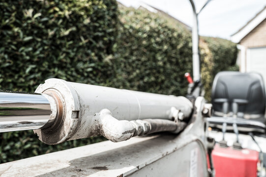 Shallow focus of a hydraulic piston seen on a mechanical digger and excavator. The hose on the piston carries the very high pressure hydraulic oil to move the shovel arm.
