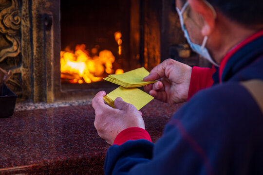 Taichung, Taiwan, January 28, 2025: Close-up of a traditional Taiwanese temple ritual involving burning joss paper and devout worshippers.