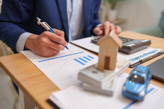 Businessman reviews mortgage documents with a calculator, evaluating property financing, home ownership, and investment planning for informed financial decisions.
