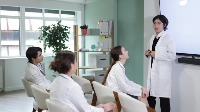 Malaysian female speaker conducts training for a medical team of specialists. Woman doctor holds a remote control in her hands and gives a presentation for young doctors. High quality 4k footage