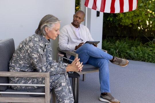 Diverse adults talking on porch, senior woman in camo uniform, African American holding tablet