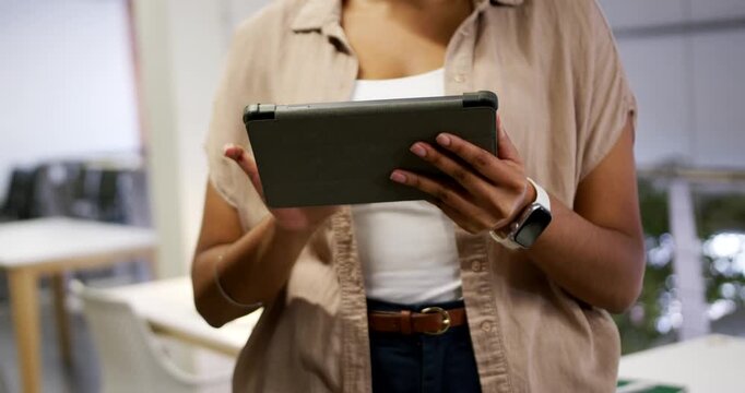 Indian woman in 20s-30s holding tablet in dark case, tapping, reading to review document in office