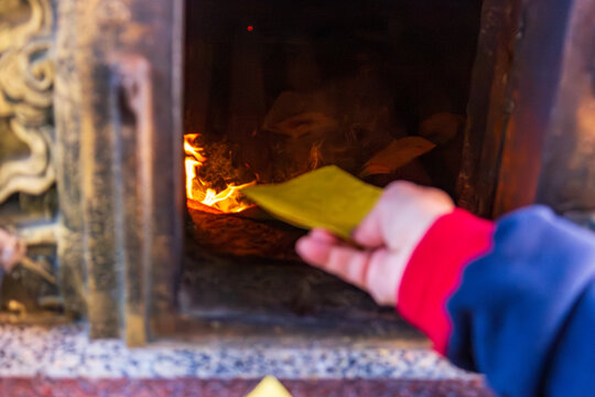 Taichung, Taiwan, January 28, 2025: Close-up of a traditional Taiwanese temple ritual involving burning joss paper and devout worshippers.
